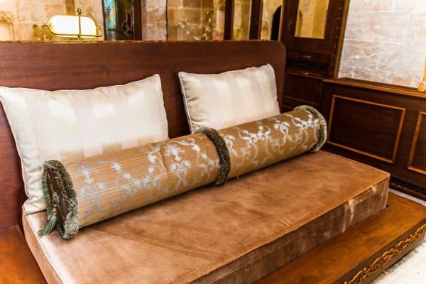 Mardius Hotel tekstil tasarımı kapsamında hazırlanan, krem rengi kırlentler ve altın işlemeli silindir yastıklar Alesta Home üretimidir.